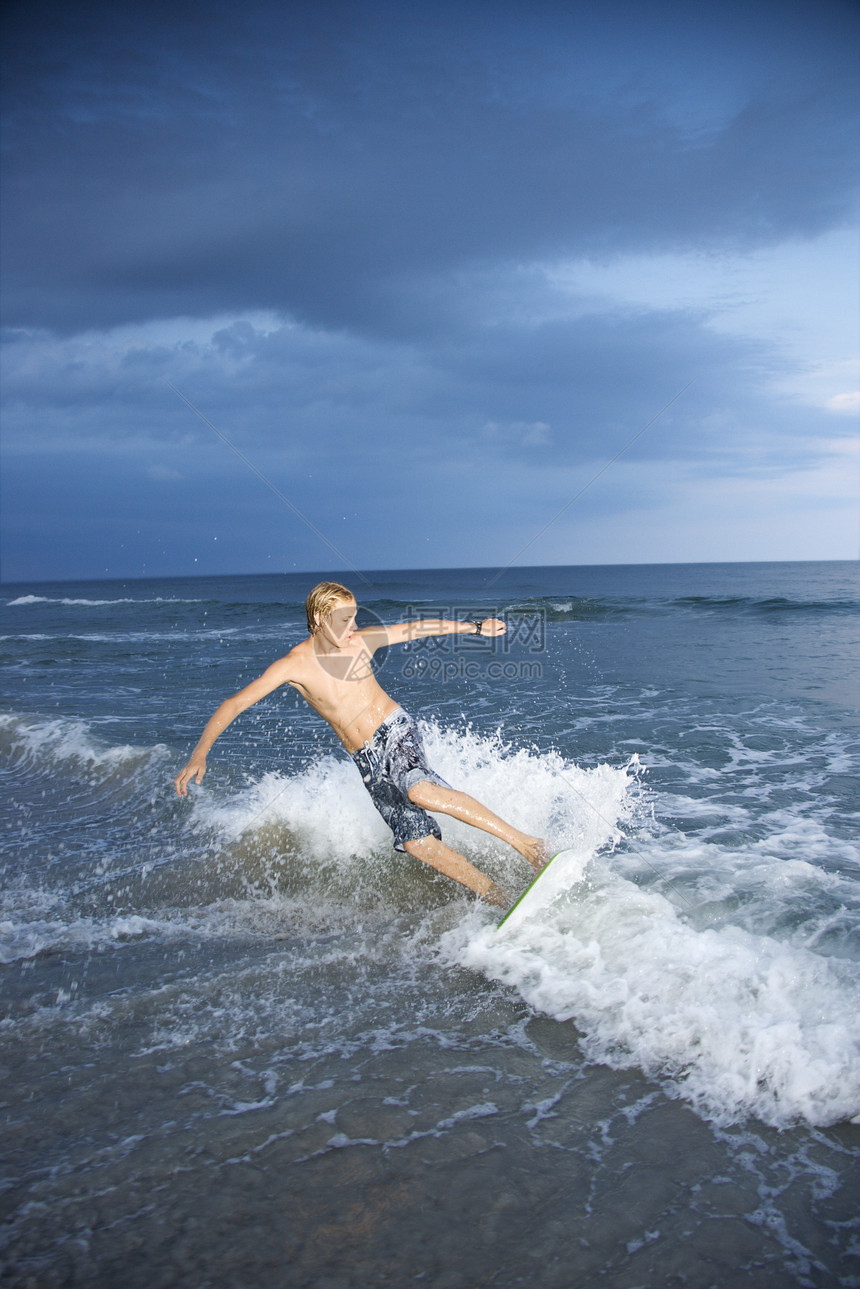男孩骑滑板波浪海滩乐趣男性闲暇骑术海洋海浪运动风景图片