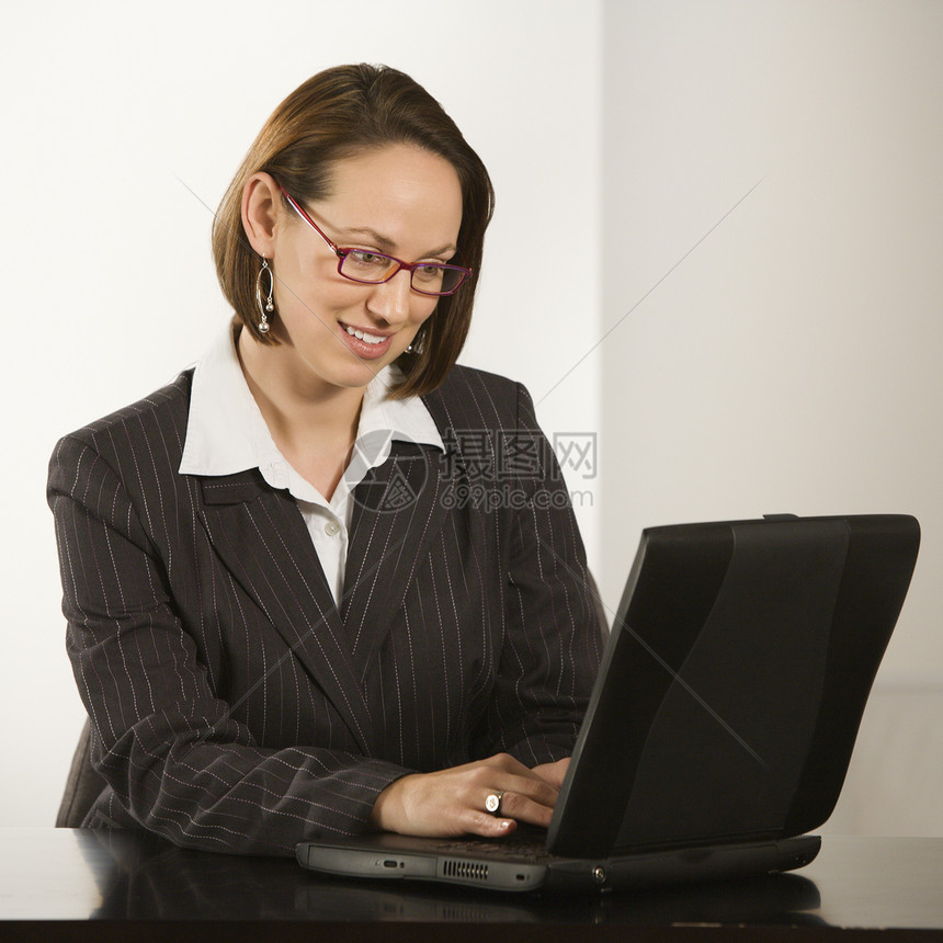 有笔记本电脑的女商务人士技术商务中年人微笑桌子女性黑发女士人士商业图片