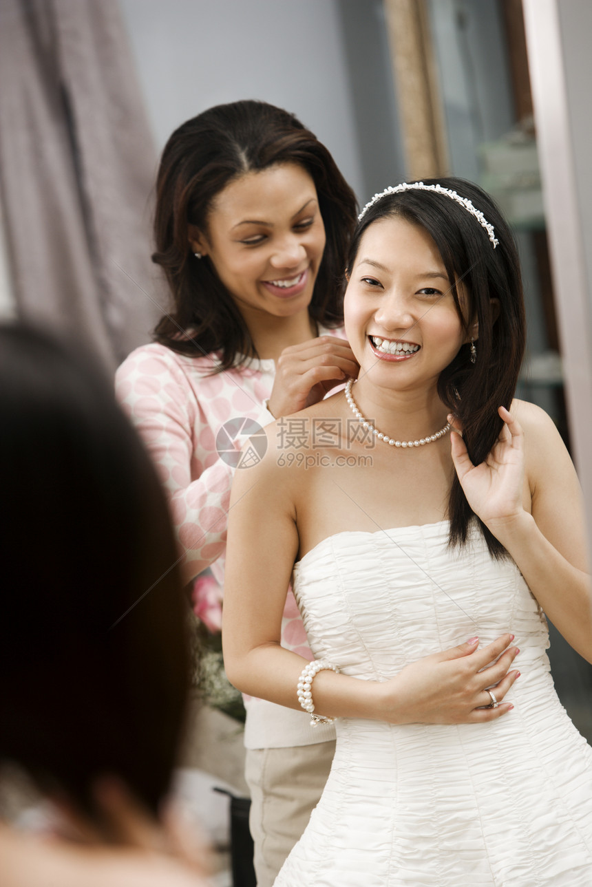 朋友帮助新娘微笑女性婚礼戏服镜子服装裙子反射女士服饰图片