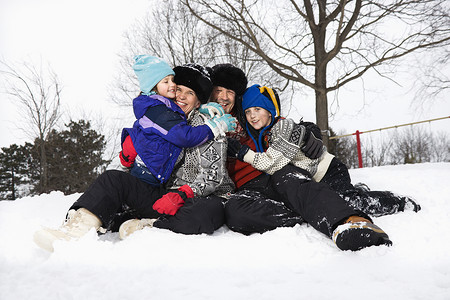 家人在雪中坐着孩子们乐趣中年男人群人父母男孩们成年人女孩们闲暇背景图片