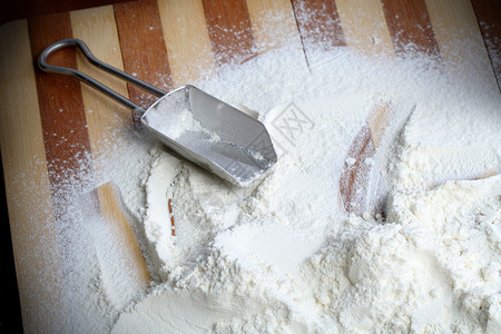 金属勺和面粉面包烘烤木板烹饪木头宏观棕色餐具粉末白色背景图片