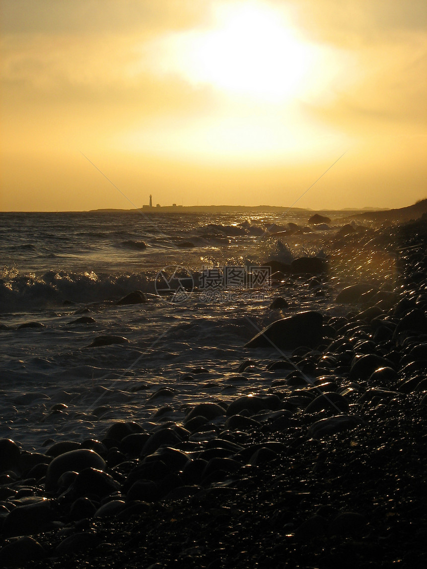 日落时灯塔海浪风暴支撑海滩图片