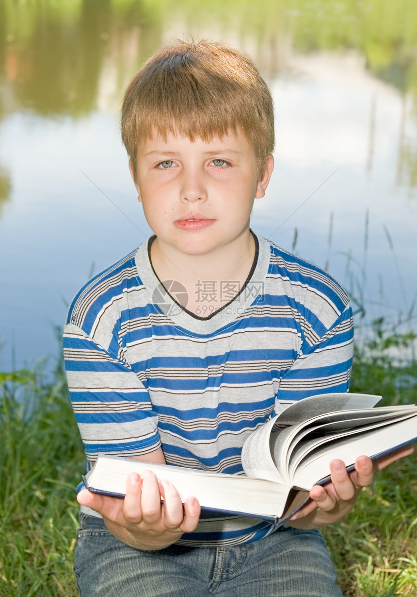 男孩读一本大书文学说谎场地页数假期教育学校公园学习男人图片