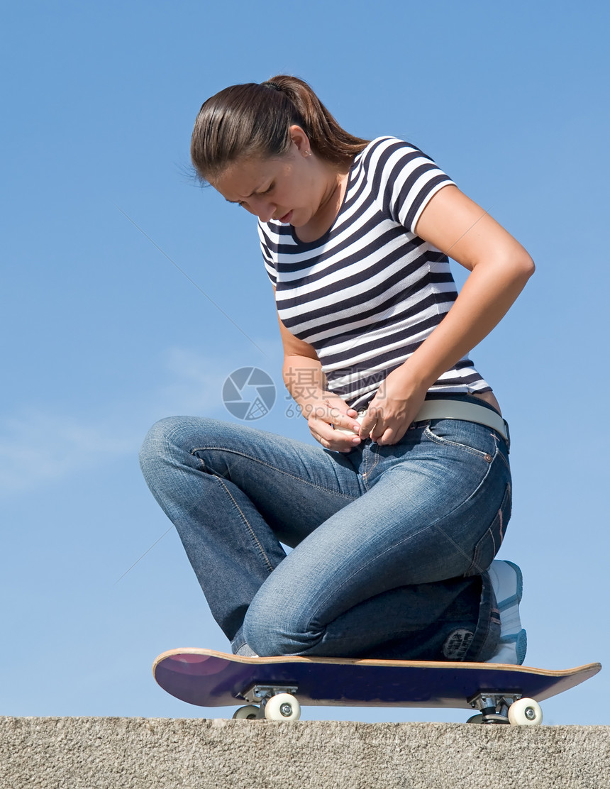 女孩在滑板上行动女性天空活动蓝色街道休息乐趣膝盖公园图片