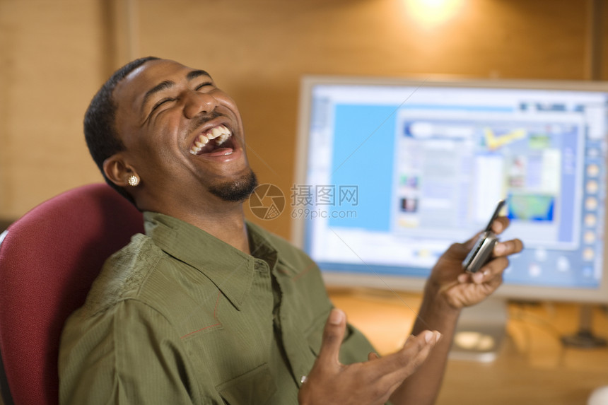 带手机和计算机的笑笑青年男子图片