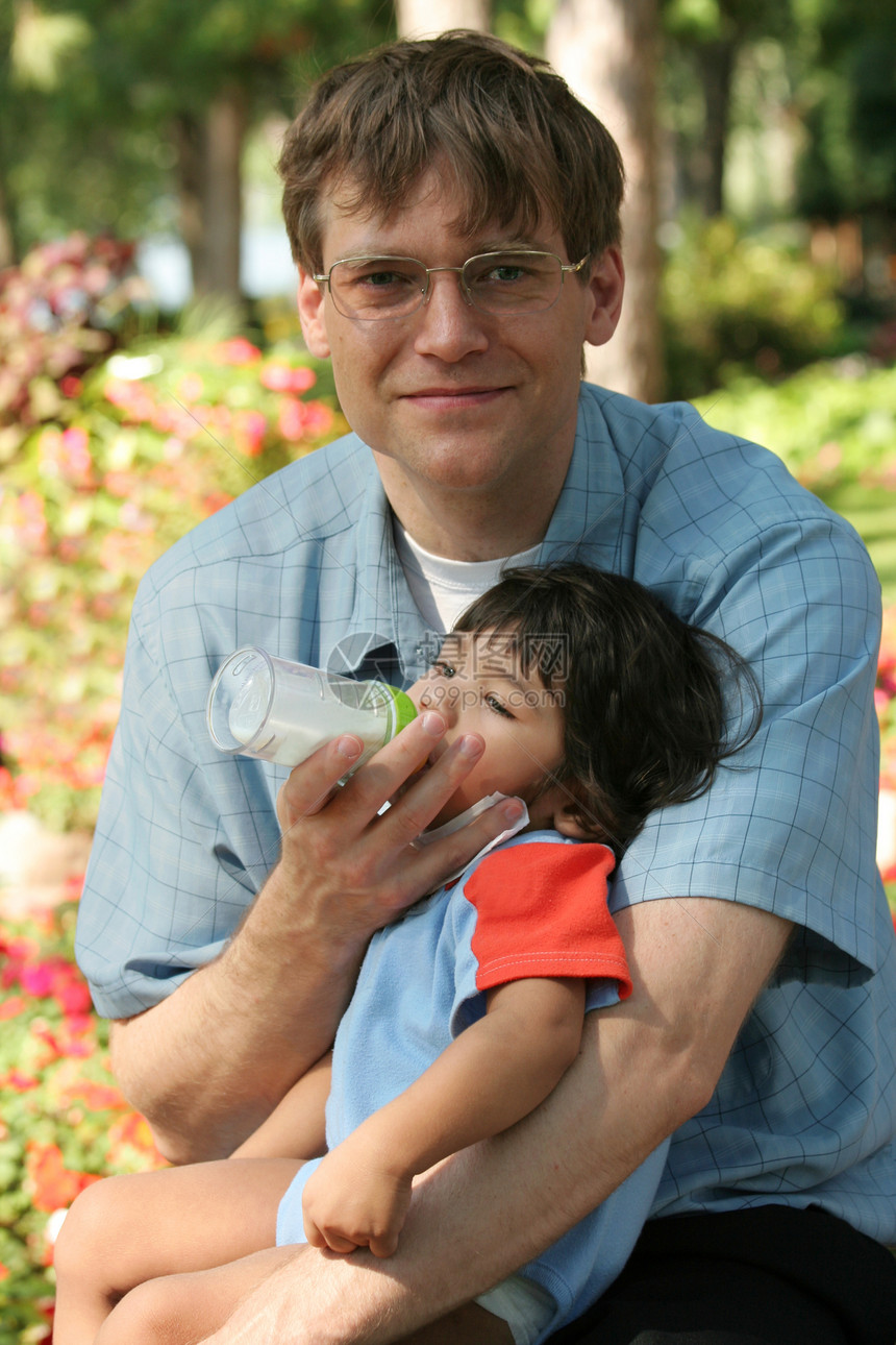 父亲在公园里喂婴儿一瓶酒爸爸家庭饥饿太阳镜儿童牛奶照顾瓶子好榜样图片