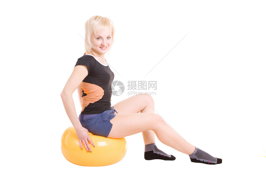 一个年轻女孩 坐在大球上为健康着想图片