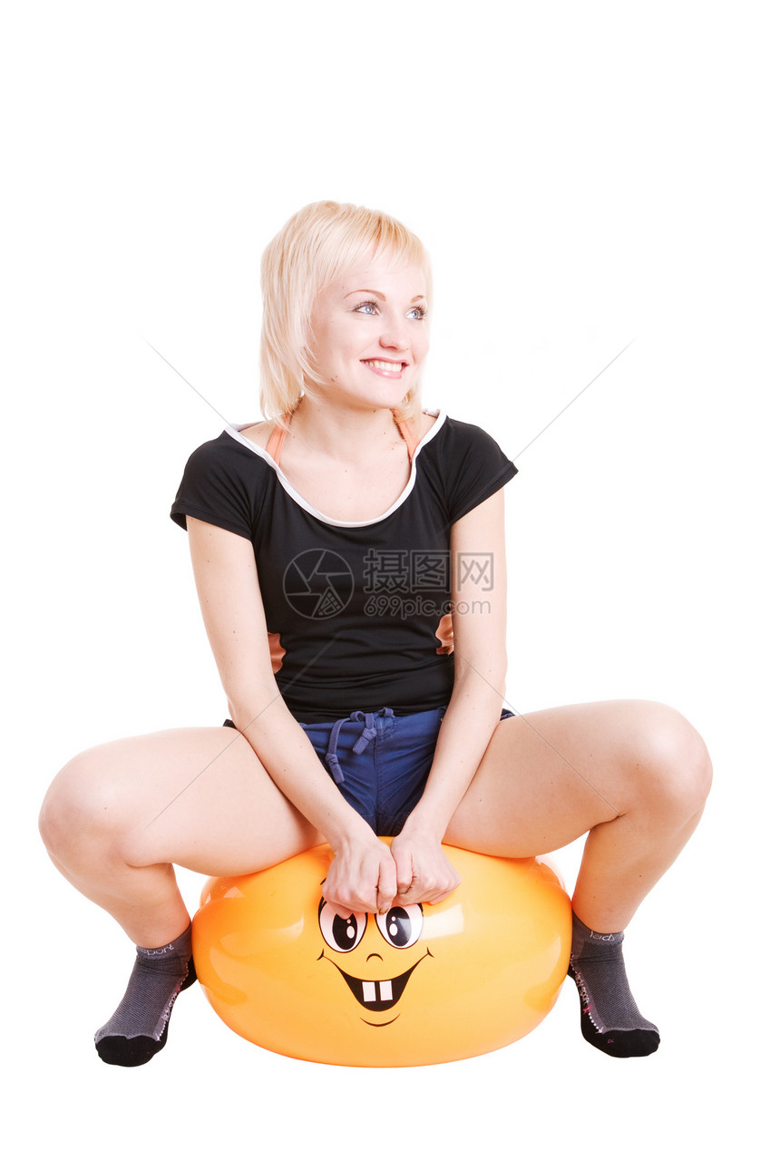 一个微笑着的年轻女子 参加健身比赛坐在一个大球上图片
