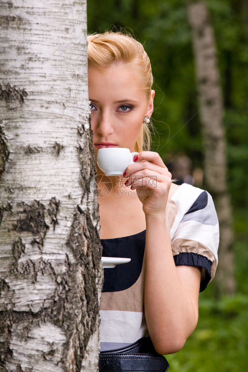 美丽的年轻女子和咖啡白色女士杯子金发裙子公园逗乐桦木女性图片