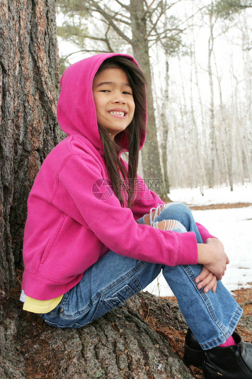 冬天坐在树下的儿童混血外套乐趣健康帽子夹克女孩微笑孩子靴子图片