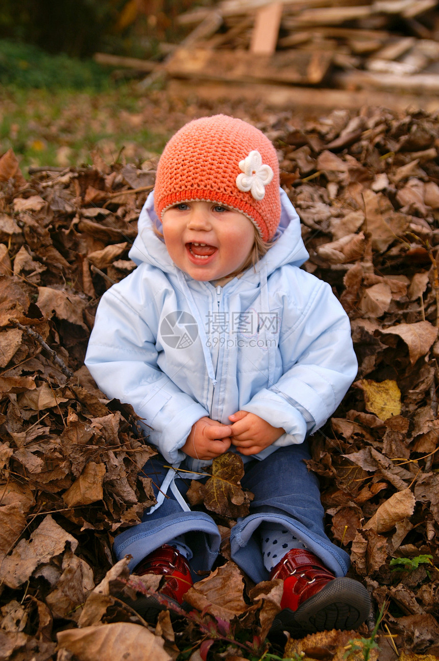 小女孩坐在树叶上微笑帽子夹克叶子青铜女孩蓝色运气图片