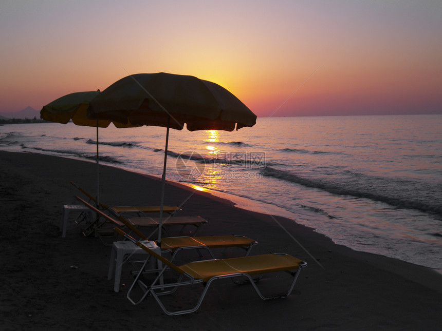 海滩上的日落日光沙滩阳伞图片