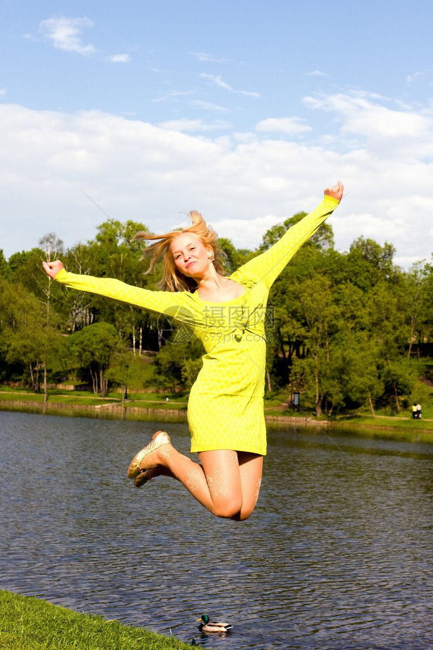 快乐的姑娘跳到河岸上身体生活运动员假期微笑天空活力运动成人女性图片