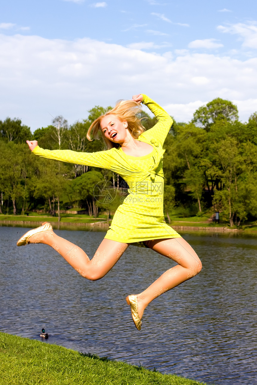 快乐的姑娘跳到河岸上蓝色假期幸福天空活力空气女孩自由生活成人图片