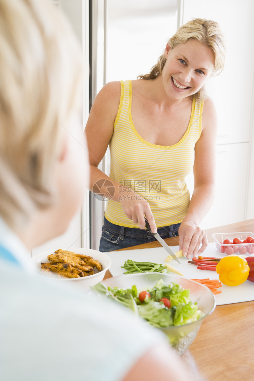 女人在准备饭菜时和朋友聊天 吃饭时间微笑团结肩视图用餐母亲晚餐食物蔬菜两个人厨房图片