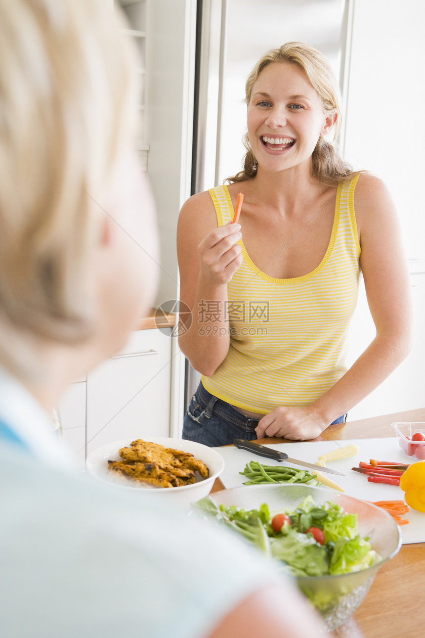 女人在准备饭菜时和朋友聊天 吃饭时间服装厨房食物休闲用餐晚餐成人家长烹饪女性图片