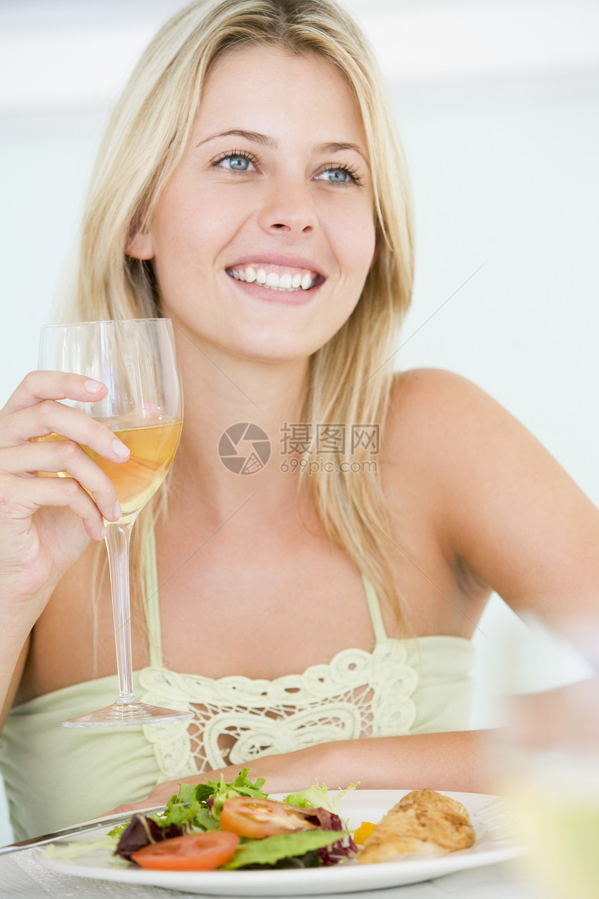 享受美食 与一杯酒共餐的年轻女子微笑蔬菜酒精刀具健康饮食饭厅酒杯吃饭休闲时间图片