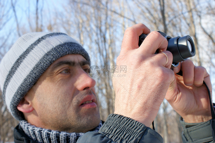男子在冬天拍下照片职业男人爱好男性镜片成人相机天空蓝色专注图片