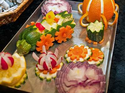 萝卜雕刻蔬菜装饰品雕塑自助餐萝卜叶子笑脸派对洋葱黄瓜沙拉绿色托盘背景