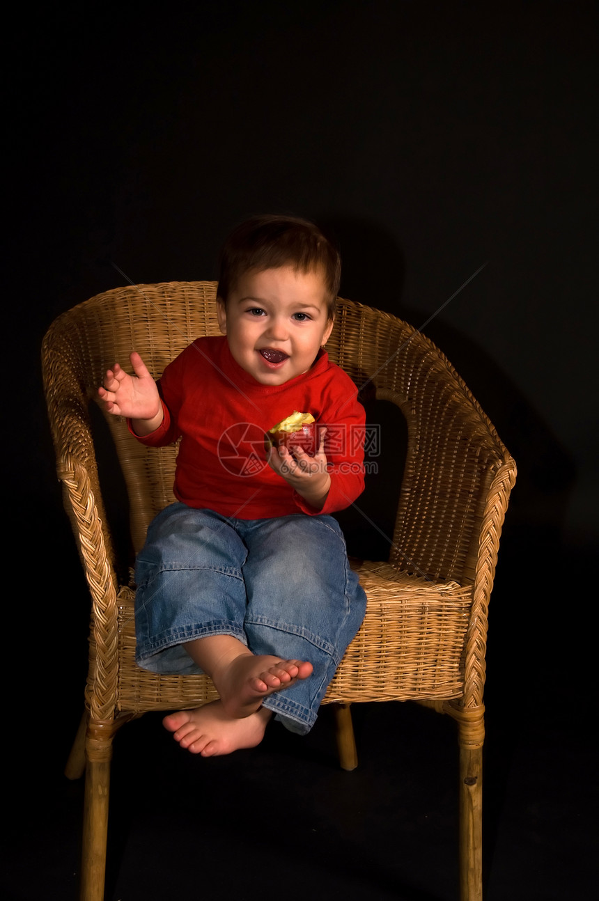 男孩坐在扶手椅上 吃苹果和喊叫图片