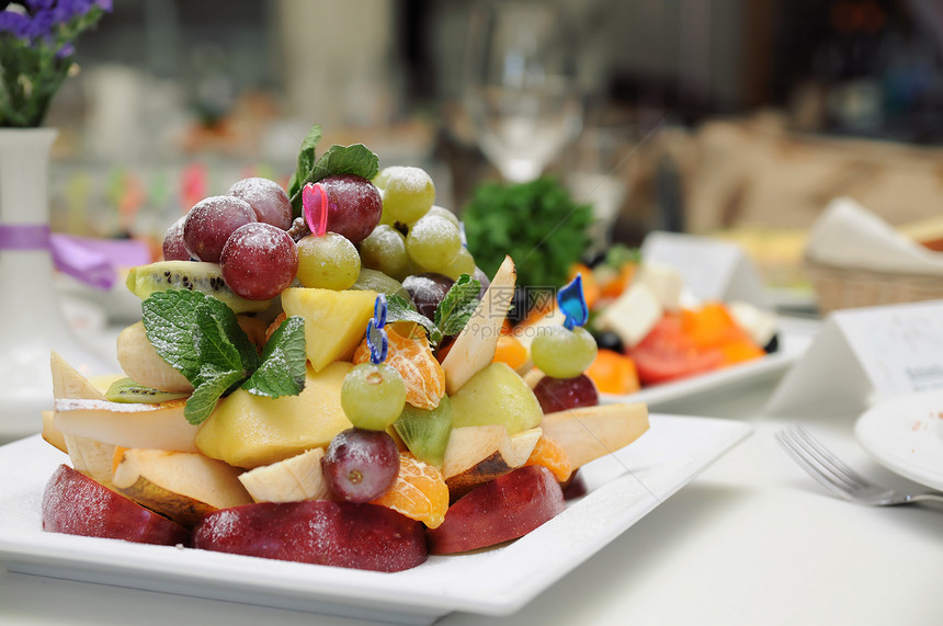 盘子上的水果沙拉蓝色橙子树叶桌子饮食午餐奇异果派对美食蔬菜图片