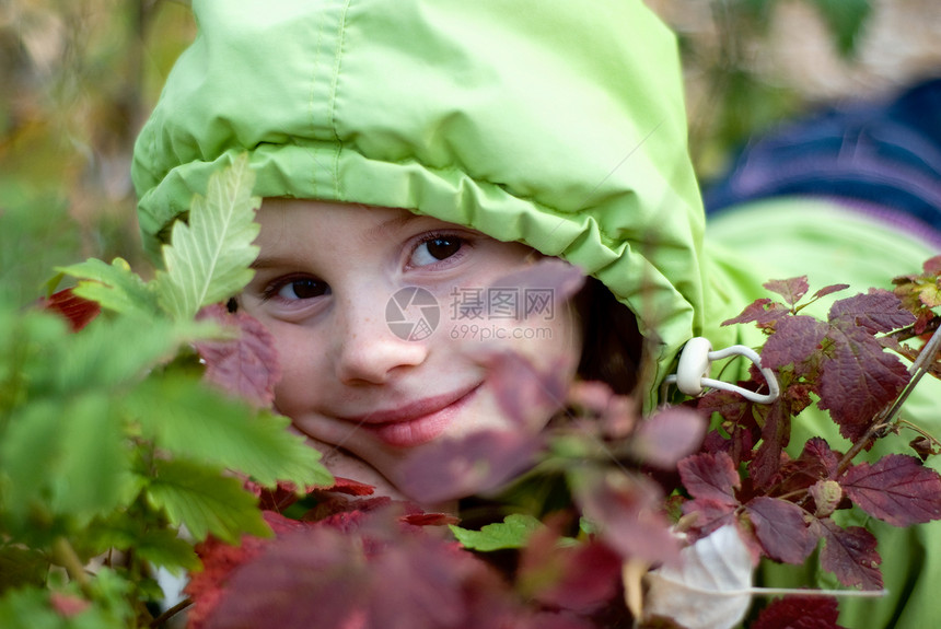 微笑的小女孩躲在树叶后面图片