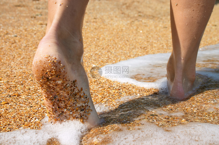 赤脚在沙海岸上冲浪图片