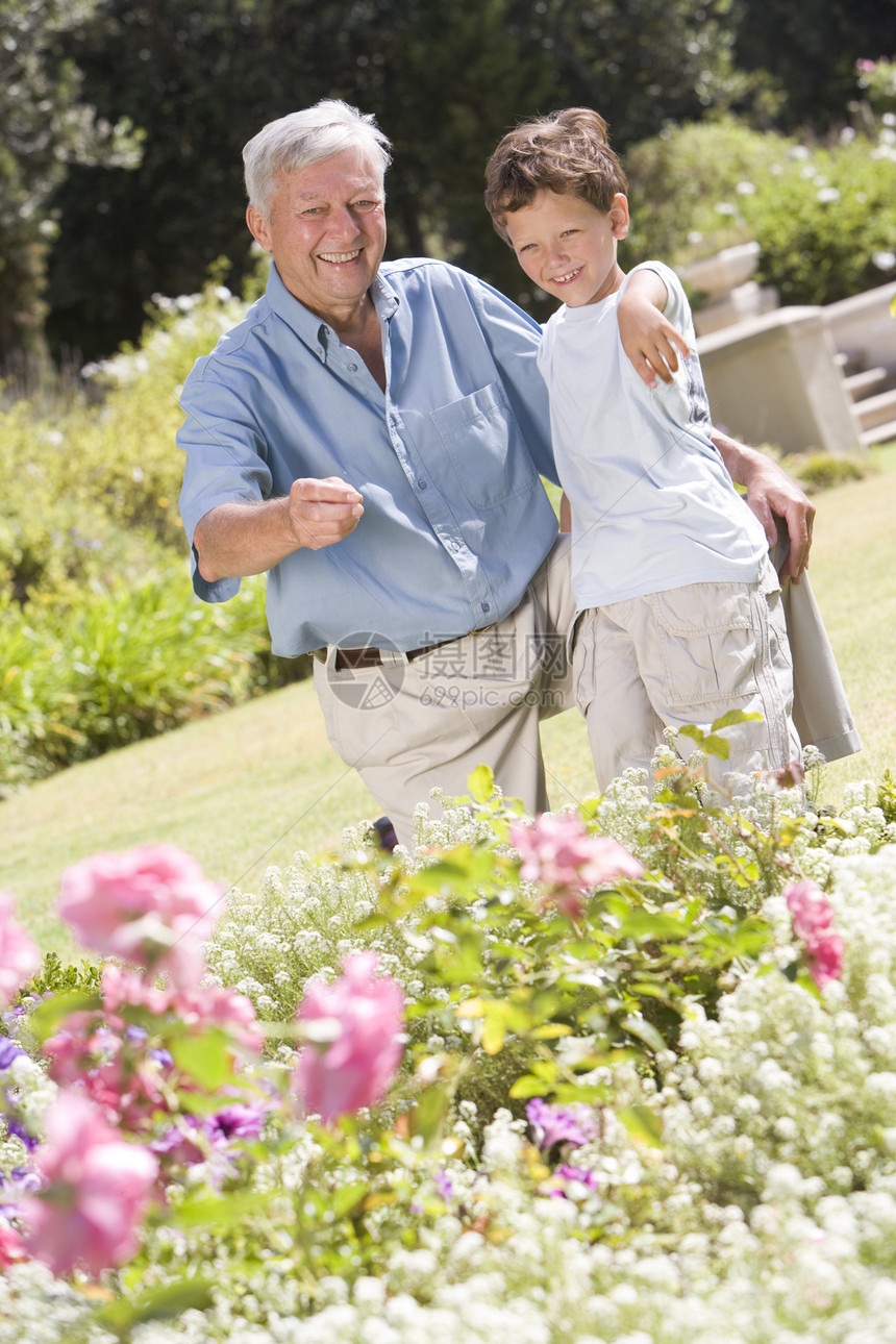 外祖父和孙子户外花园中指着植物院子男人庭园偏移角两个人祖父母花坛视角男性蹲伏图片