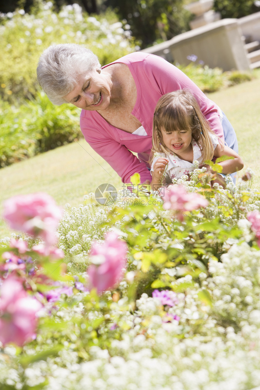 外祖母和外孙孙女在花园的户外露天微笑孙子祖父母女孩蹲伏祖母植物亲密感孩子花坛花园图片