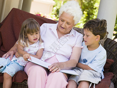 外祖母向孙辈朗读孙女阅读露台甲板男生女孩保姆祖父母祖母微笑背景图片