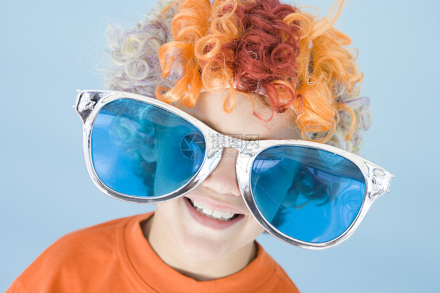 带着小丑假发和墨镜微笑的年轻男孩戏服爆头派对眼镜孩子们青少年色调影棚男性水平图片