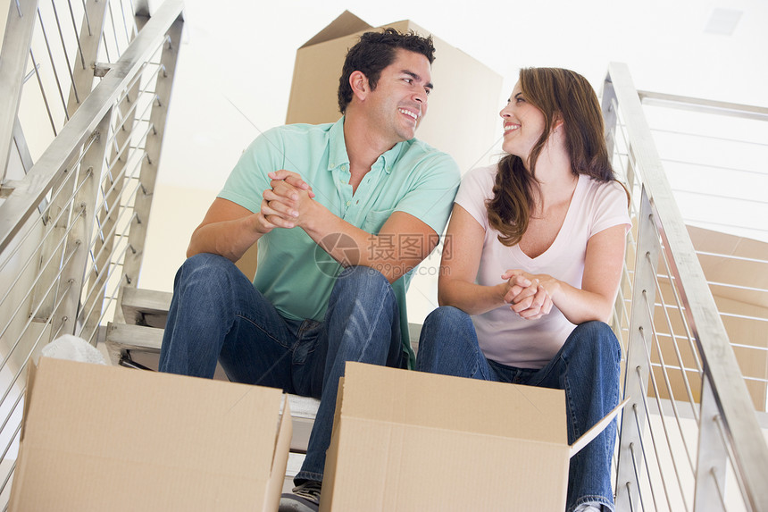 一对坐在楼梯上 带着盒子在新家微笑的一对夫妇两个人男性房子男人购买者高架休息财产女性搬运箱图片