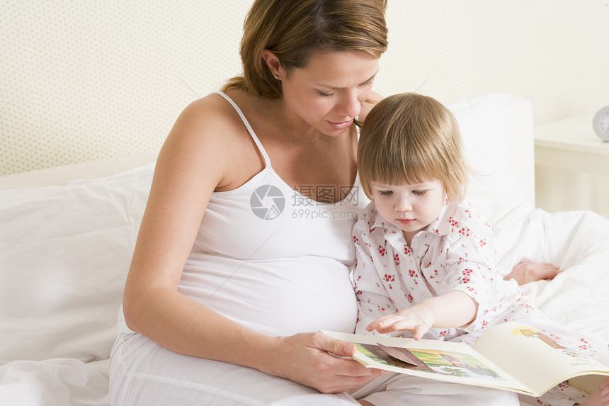 与女儿一起在卧室阅读书中的怀孕妇女女性时间家庭待产孕妇装女士妈妈孕产两个人就寝图片
