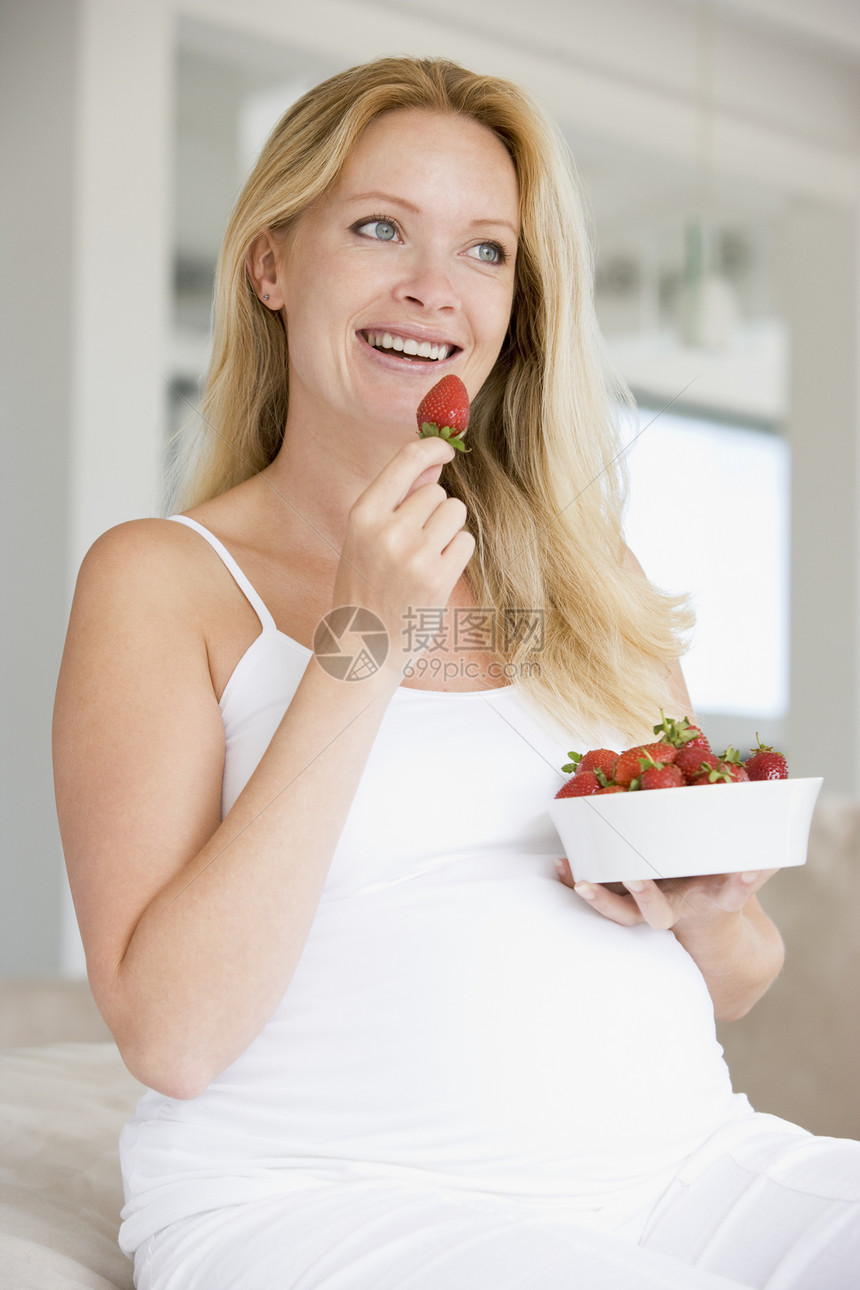 带着一碗草莓的孕妇微笑着妈妈待产新妈妈家长水果女性准妈妈家庭怀孕孕妇装图片