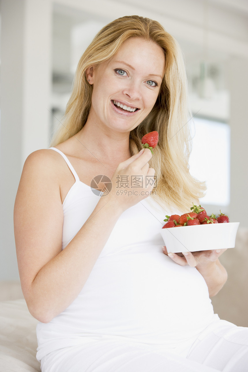 带着一碗草莓的孕妇微笑着饮食新妈妈准妈妈家庭小吃水果孕妇装享受怀孕待产图片