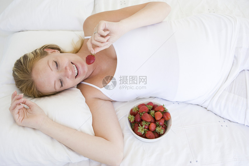 躺在床上的孕妇带着一碗草莓 微笑着女性待产享受饮食新妈妈妈妈准妈妈小吃孕产孕妇装图片