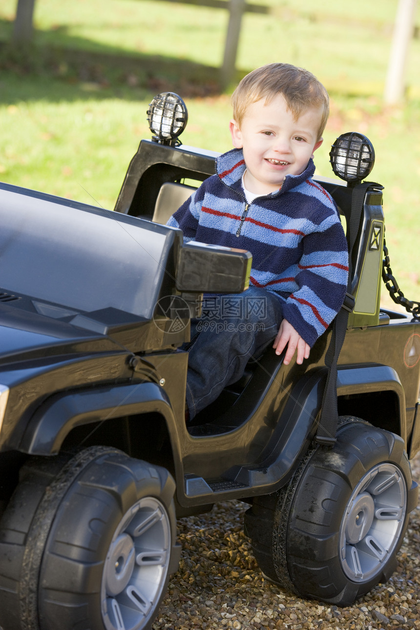 年轻男孩在户外玩耍 坐在玩具卡车上微笑图片