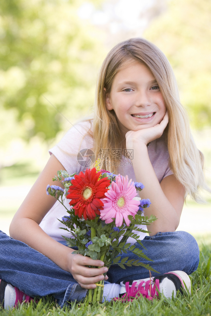 年轻女孩拿着鲜花微笑孩子女性青春期花束农村花朵长度相机公园孩子们图片