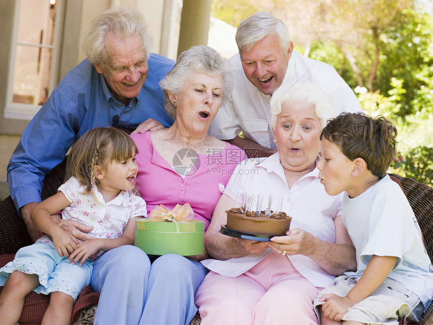 祖父母和孙孙子在有蛋糕和礼物的院子上图片
