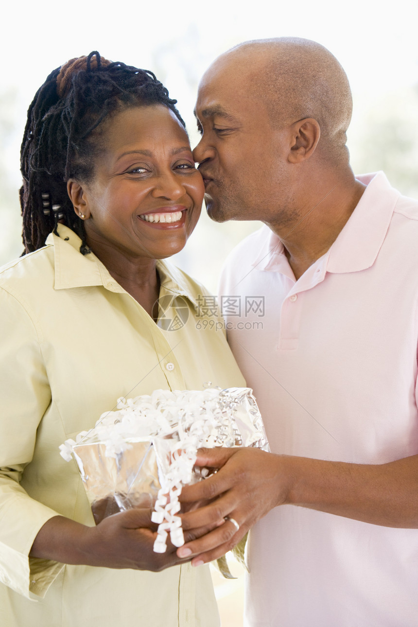 丈夫和妻子怀着礼物的亲吻和微笑图片