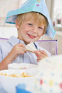 少吃多动小男孩在派对上坐在餐桌边 带着一个三明治笑着背景