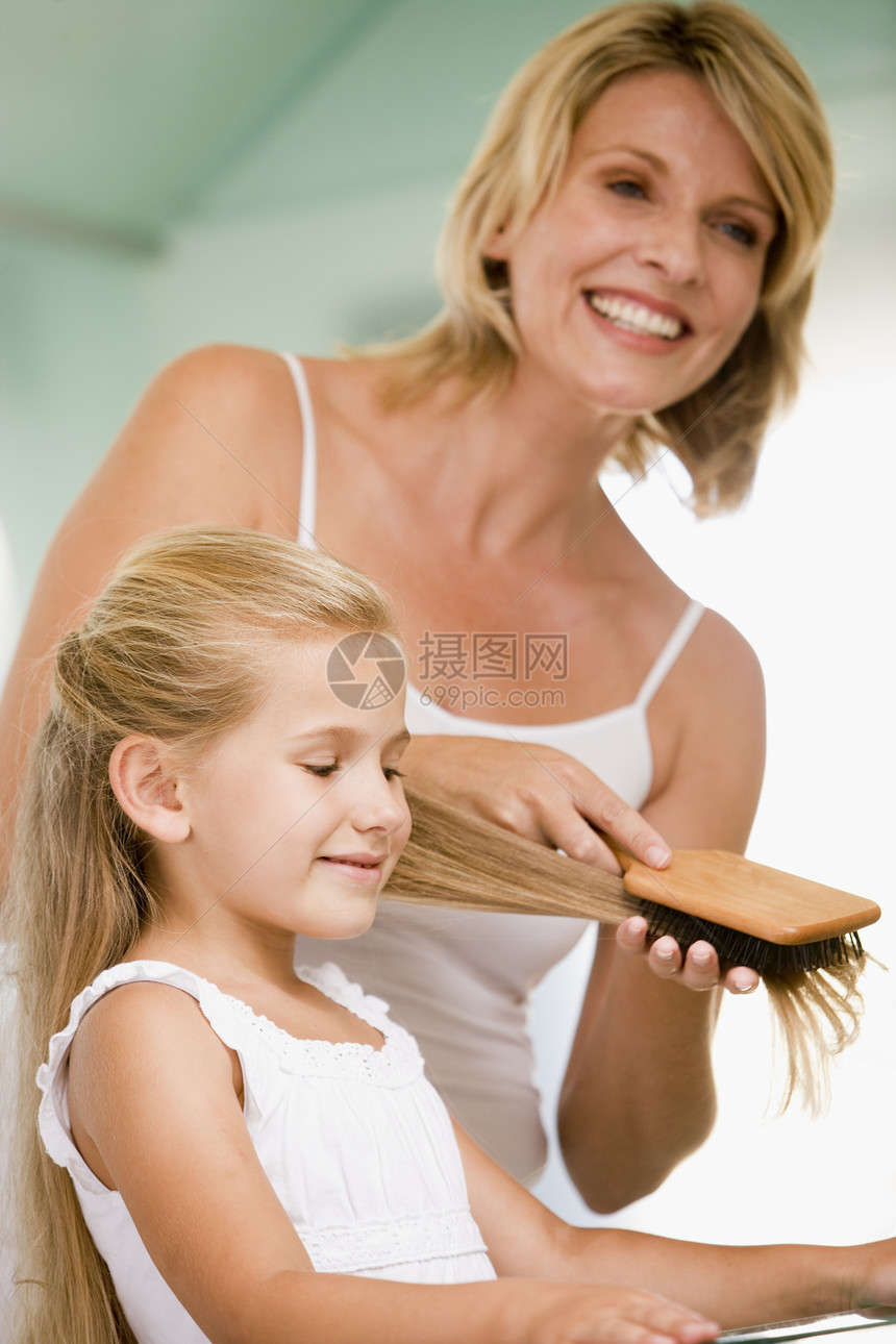 洗手间女人梳年轻女孩的头发图片