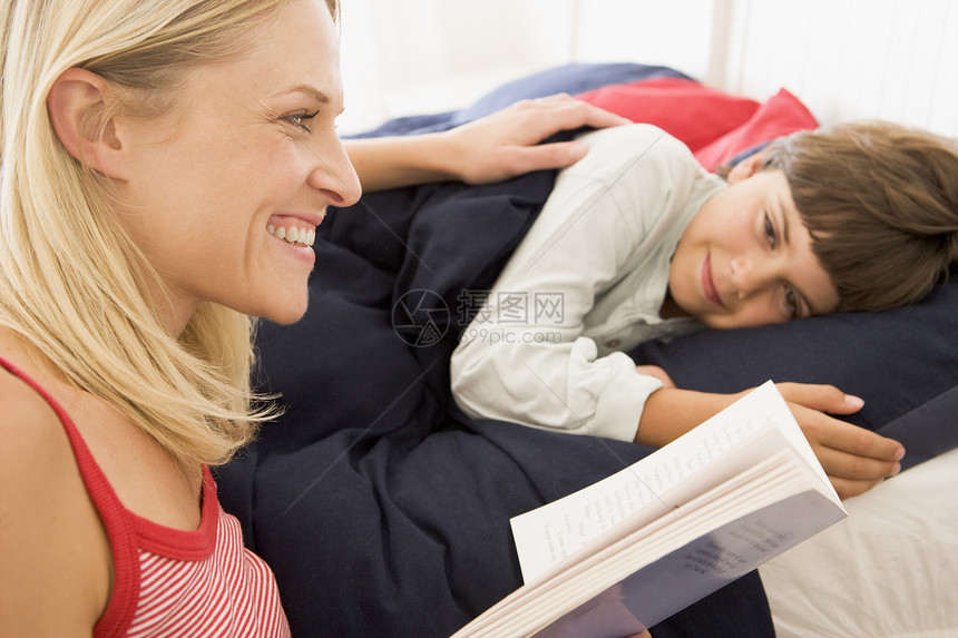 女人给在床上笑着的男孩看书图片