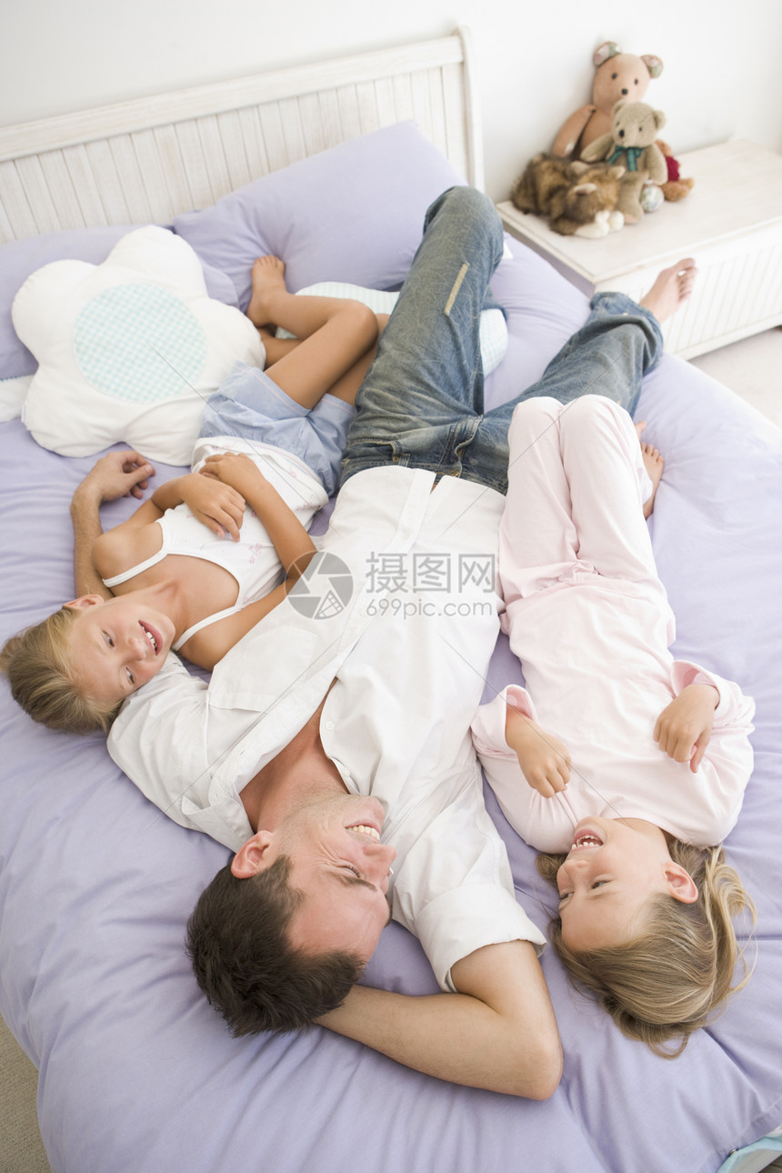 男人和两个年轻女孩躺在床上微笑三个人孩子们亲热女子睡衣女儿女人爸爸孩子卧室图片