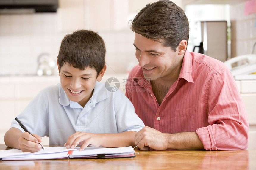 男人在厨房帮助小男孩做功课和微笑拉丁爸爸家长男性两个人监督家庭作业孩子们文件夹笔记图片