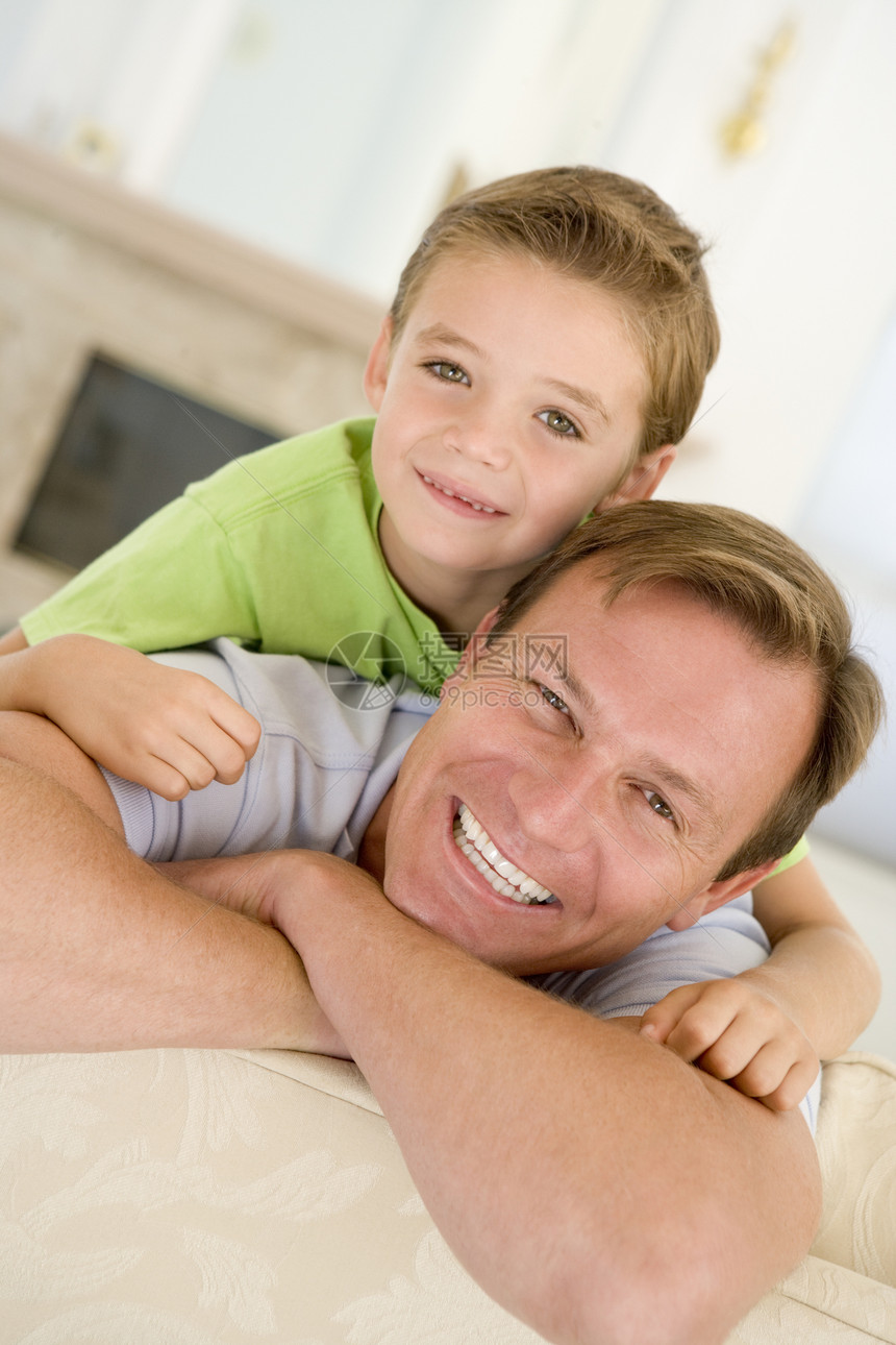 坐在客厅里笑着的男子和男孩家长儿子男人中年两个人家庭生活沙发拥抱男性孩子们图片