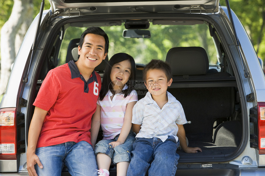 男人和两个孩子坐在面包车后面微笑着女儿相机尾门爸爸姐姐三个人树干兄弟旅行农村图片