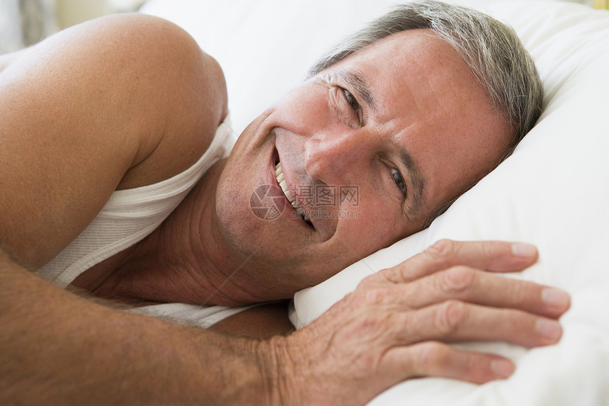 男人躺在床上微笑着水平睡眠睡衣苏醒相机卧室退休男性丈夫休息图片