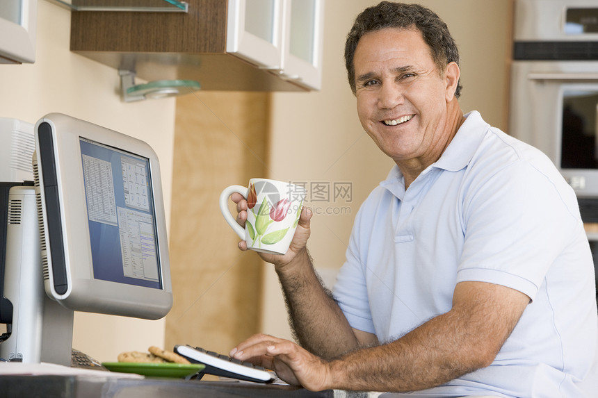 厨房里的男人 带着电脑和咖啡笑着的咖啡退休成人水平工作站技术男性相机互联网冲浪微笑图片