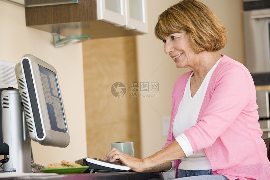 厨房里的女人 带着电脑和咖啡笑着的咖啡女性女士成人桌子水平冲浪微笑退休技术互联网图片